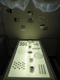 a table that has some cups on it with lights in the room behind it and pictures on the wall