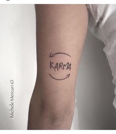 a person with a tattoo on their arm and the word karma written in black ink