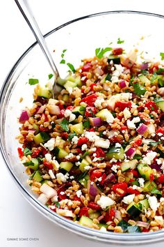 a bowl filled with lots of food on top of a white table next to a fork