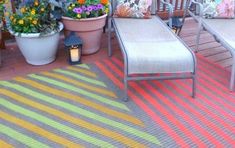 an outdoor patio with chairs and potted plants on the deck area, along with a striped rug