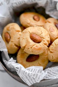 almond cookies in a metal bowl on top of newspaper