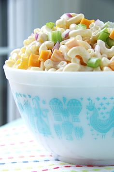 a white bowl filled with macaroni salad on top of a colorful table cloth