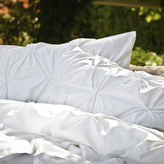 an unmade bed with white sheets and pillows on top of it in the sun