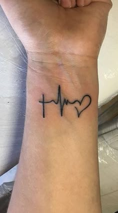 a woman's wrist with a heart and heartbeat tattoo on it