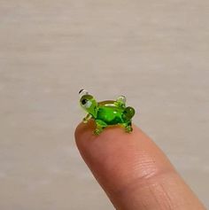 a tiny green frog sitting on top of a finger