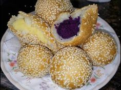 several sesame seed rolls on a plate with purple stuff in the middle and one cut open