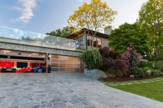 a car garage with two cars parked in front of it and landscaping around the driveway