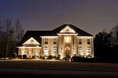 a large house lit up at night with christmas lights on the front and side windows