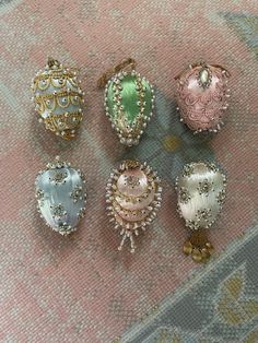 six different colored glass ornaments sitting on a pink carpet next to a rug with an ornate design