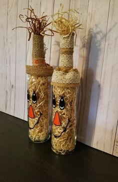 two glass bottles with straw wrapped faces on them