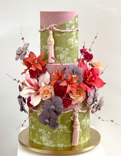 a three tiered cake decorated with flowers and tassels