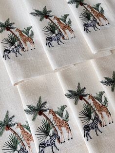 four napkins with giraffes, zebras and palm trees on them