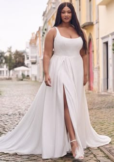 a woman in a white dress standing on a cobblestone street