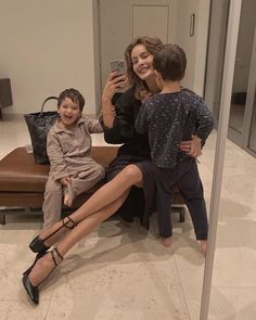 a woman taking a selfie with her two children in front of a mirror,