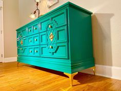 a green dresser with gold handles and knobs on the drawers in a living room