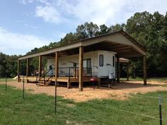 a mobile home sits in the middle of a grassy area with a fence around it