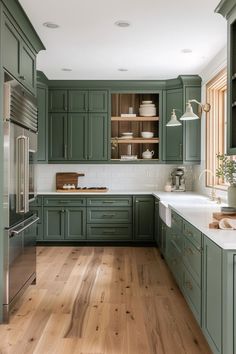 a kitchen with green cabinets and white counter tops, hardwood floors, and stainless steel appliances