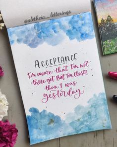 a piece of paper with writing on it next to some flowers and pens in the background