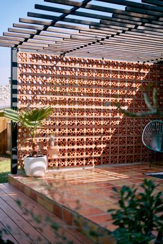 an outdoor area with a pergolated wall and potted plants