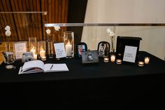 a black table topped with pictures and candles next to a book on top of a table