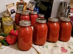 there are many jars with food in them sitting on the kitchen counter next to some vegetables