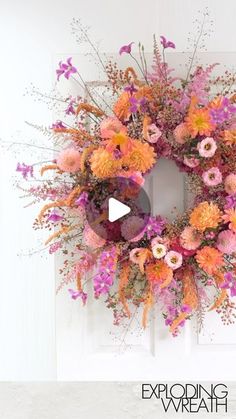 an orange and pink wreath is hanging on a door with the words exploding beneath it