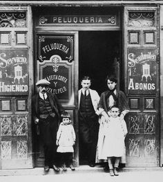 three adults and two children standing in front of a building with advertisements on the doors