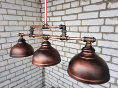 three industrial style lights hanging from a brick wall