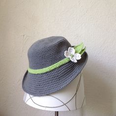 a crocheted hat with a flower on the brim and ribbon around the brim