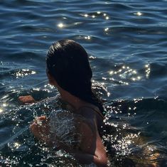 a woman swimming in the water with her back to the camera