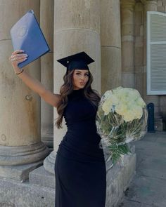 a woman in a graduation cap and gown holding a bouquet of flowers with her hand