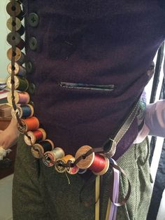 a person wearing a belt with buttons and thread on it's back, in front of a mirror