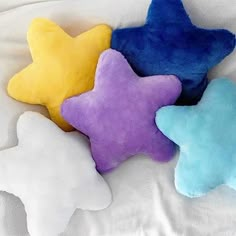 three star shaped pillows on a white sheet with blue, yellow and purple stars in the middle