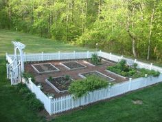 an aerial view of a garden in the middle of a yard with white picket fence