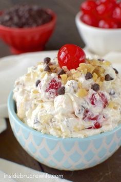 a bowl filled with fruit salad next to two bowls of chocolate chips and cherries