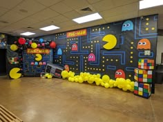 an office decorated with pac - man balloons and video game themed backdrops for a birthday party