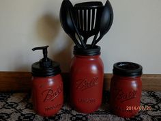 three red mason jars with black lids and whisk attachments are sitting on a rug