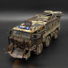 a toy army vehicle with lights on it's roof and front wheels, sitting on a black surface