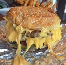 a cheeseburger with lots of melted cheese on it's bun and fries