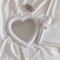 a heart shaped mirror sitting on top of a bed next to a spool of thread