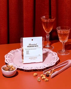 a table topped with two wine glasses and a plate filled with nuts next to a menu