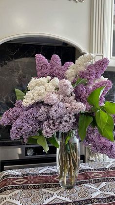 a vase filled with purple and white flowers sitting on top of a table next to an oven