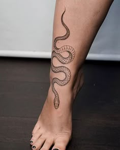 a woman's foot with a snake tattoo on it