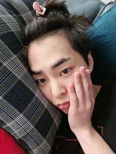 a young man laying on top of a bed next to a pillow