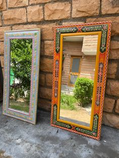 two mirrors sitting next to each other near a brick wall