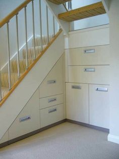 an empty room with some drawers under the stairs