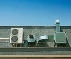 an air conditioner on the side of a building next to two chairs and a window