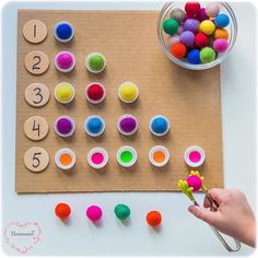 a child's hand is holding a flower next to some felt balls and numbers