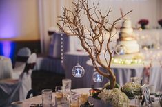 the table is set up for a wedding reception with decorations and flowers on it, along with an ornament tree