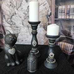 two black candlesticks sitting on top of a table next to a cat figurine